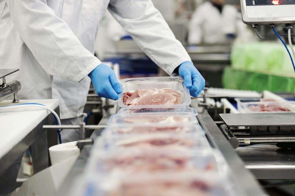 Meat producer working on packaging pieces of chicken.