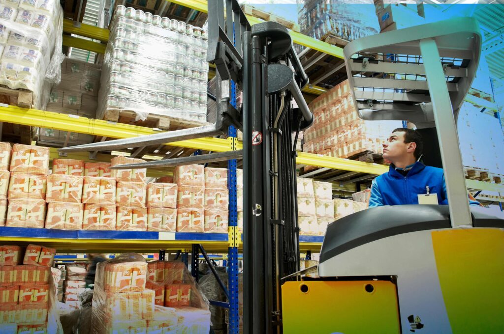 A factory worker on a forklift picking up a pallet of items - food packaging - Dassault Systemes blog