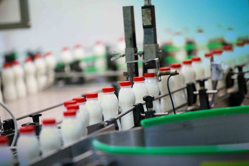 Milk bottles on a conveyor belt in a factory - food packaging - Dassault Systemes blog