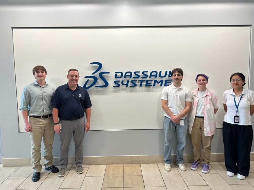 The SOLIDWORKS Training Team transforming STEM education: Sam, Sofia, Max and Johanna and their manager pose in front of the Dassault Systèmes logo on their last day of work.