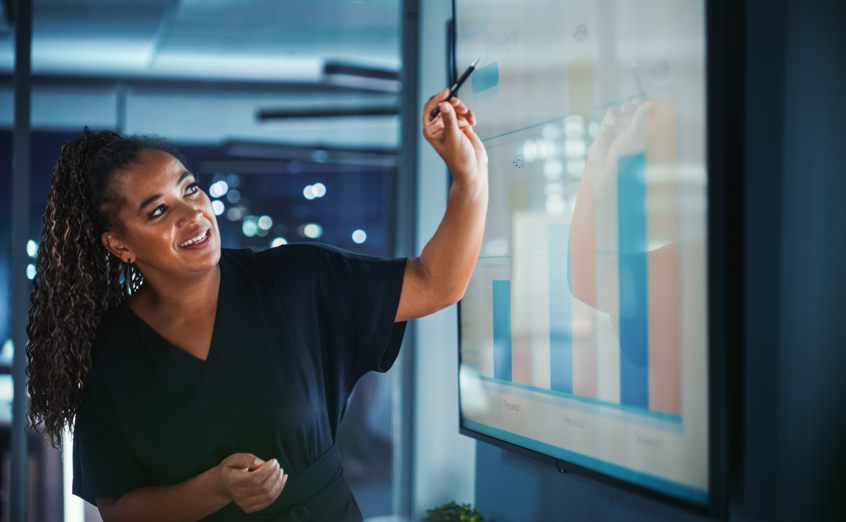 woman pointing at successful business metrics on a screen