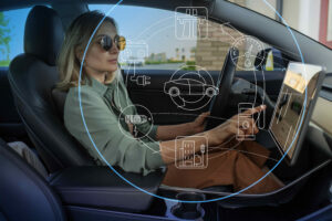 Young female driver sitting in car and pointing at car dashboard display 