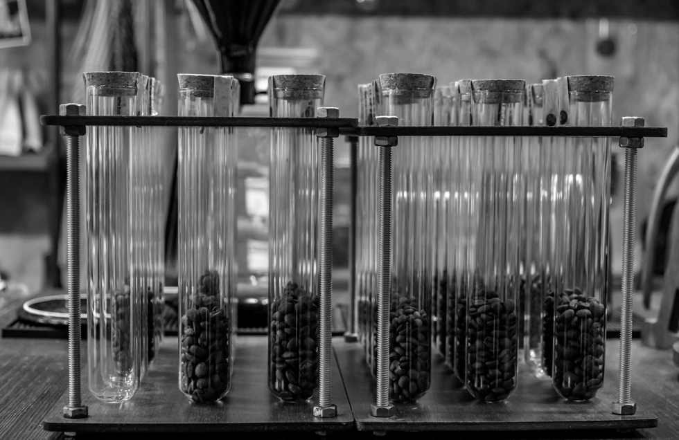 a black and white image of coffee beans in test tubes meant to reflect older, more data methodologies to test food