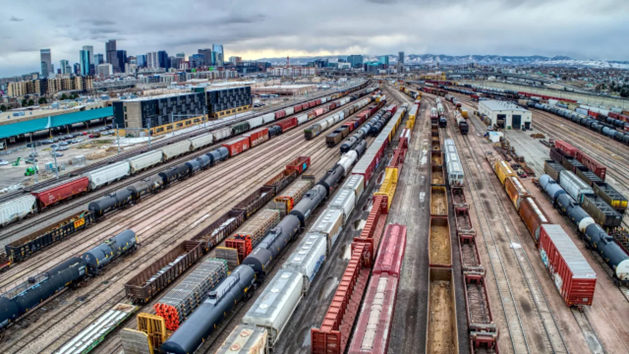 Freight rail yard with rows of rail cars and a city skyline